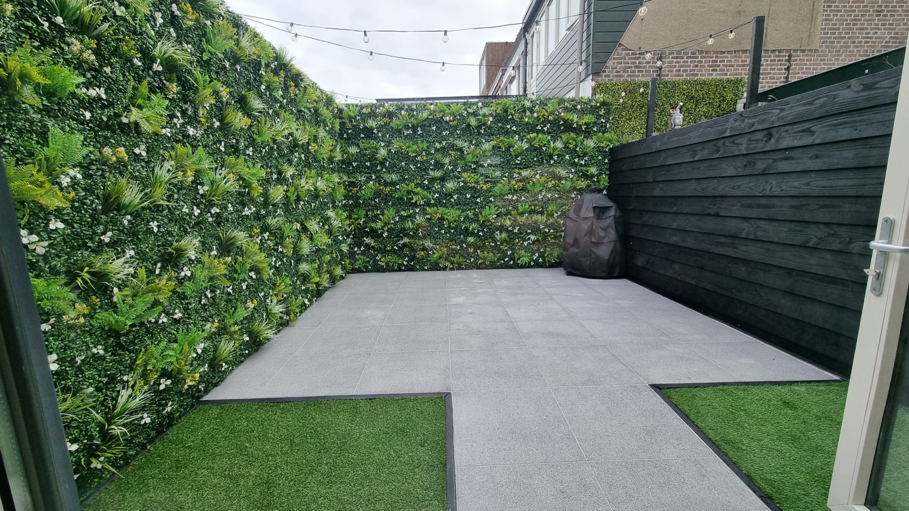 Moderne stadstuin met groenwand en tegelterras