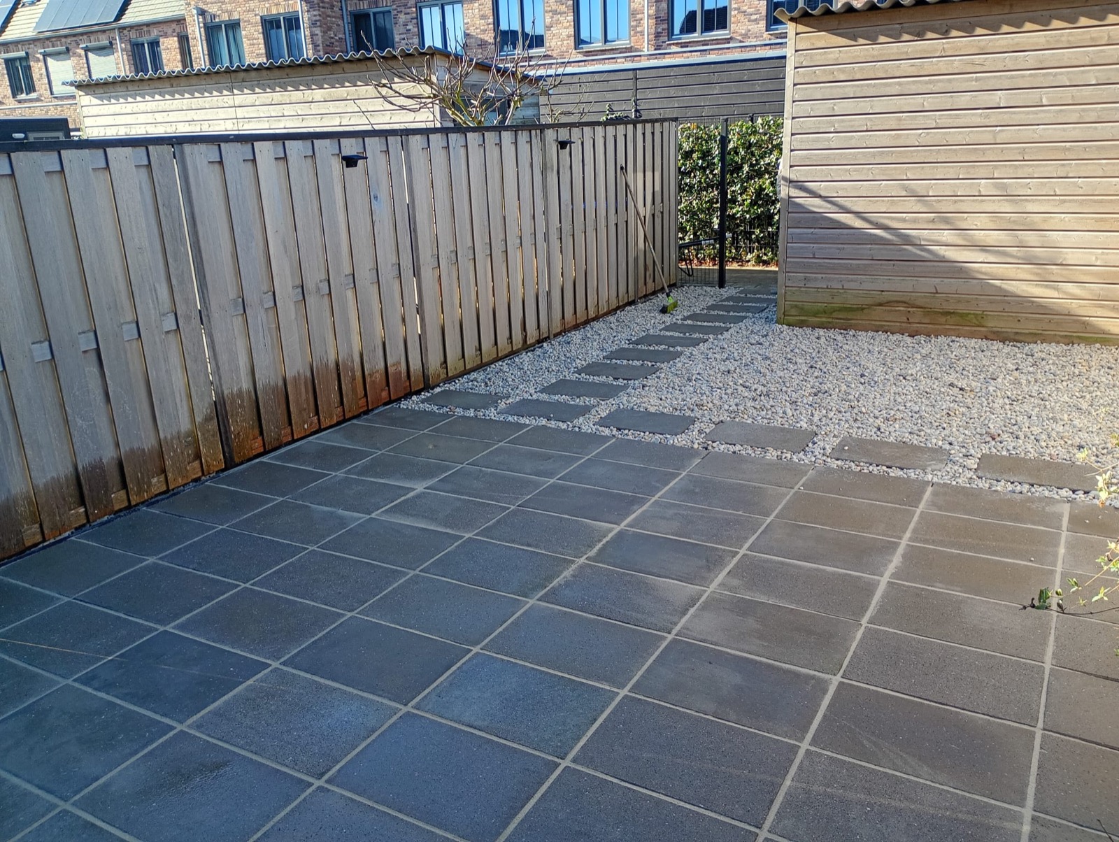 Tegelpad met grind en houten schutting