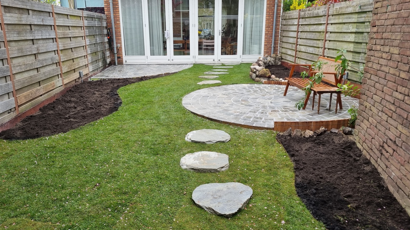 Tuin met rond natuurstenen terras en stapstenen